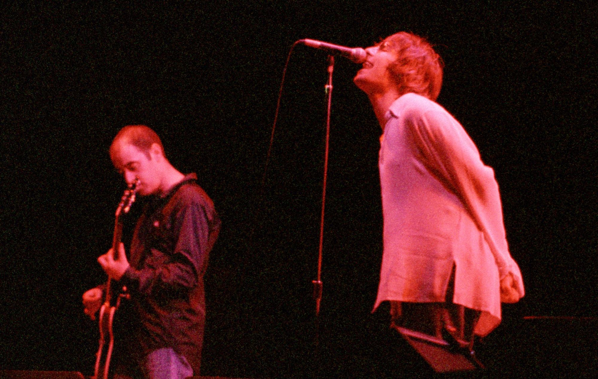 Paul 'Bonehead' Arthurs and Liam Gallagher performing on stage with Oasis in 1996.