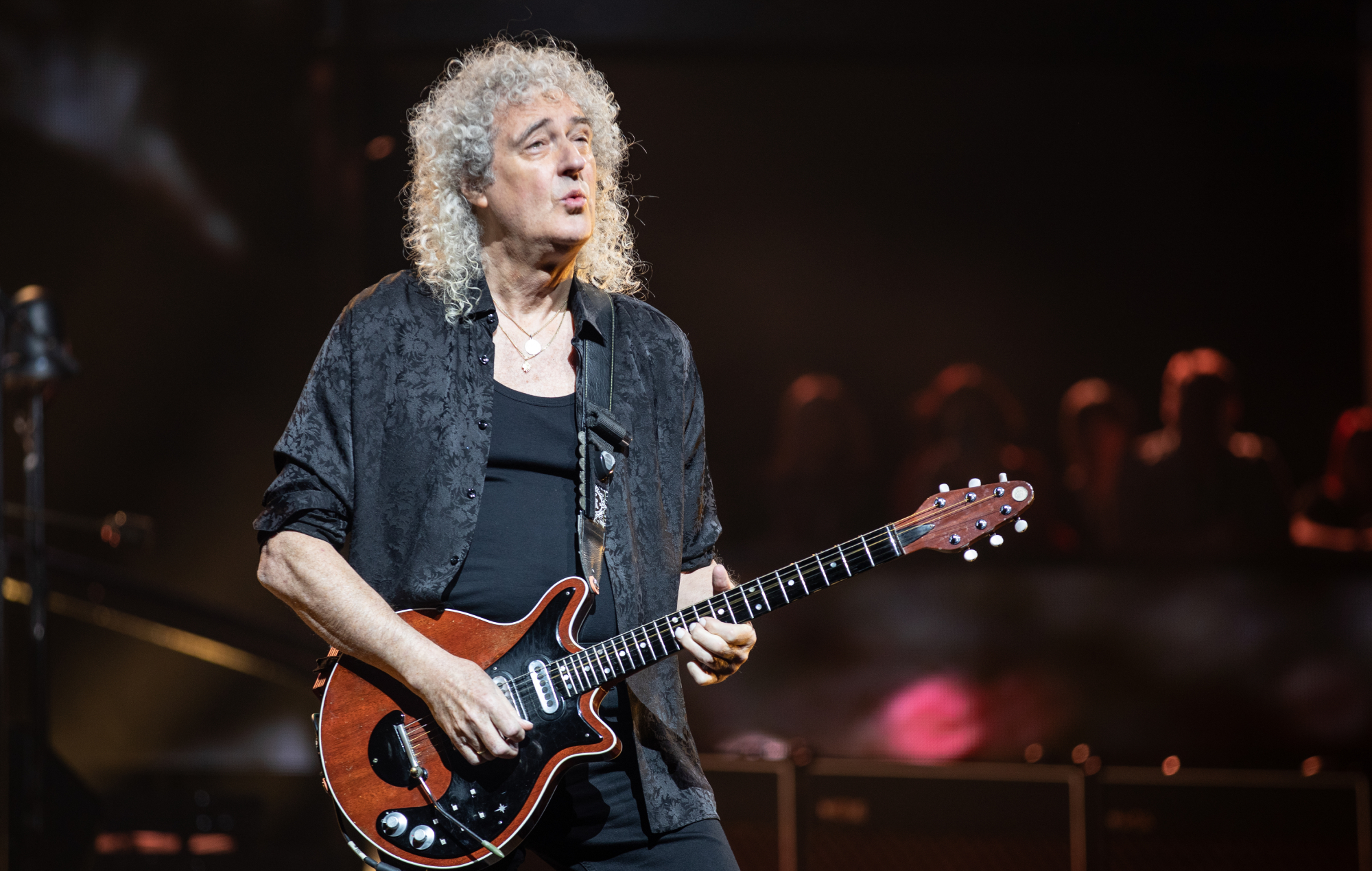 Brian May performs on stage with Queen