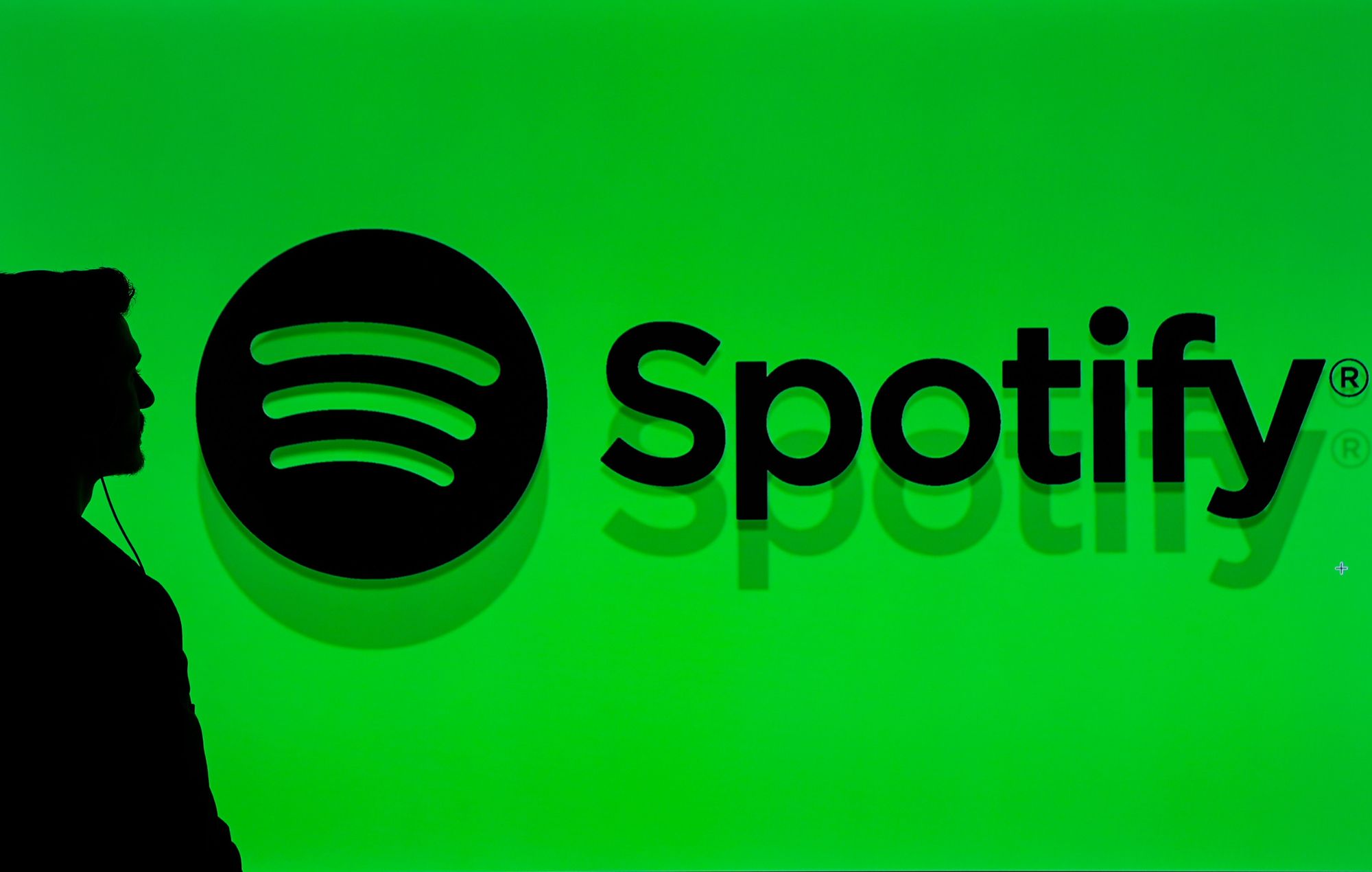 A person walks through a screen displaying the Spotify logo